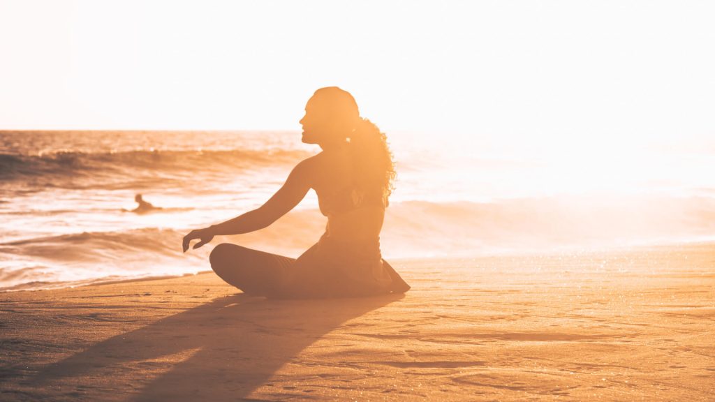 Girl sitting on the beach as the sunrises